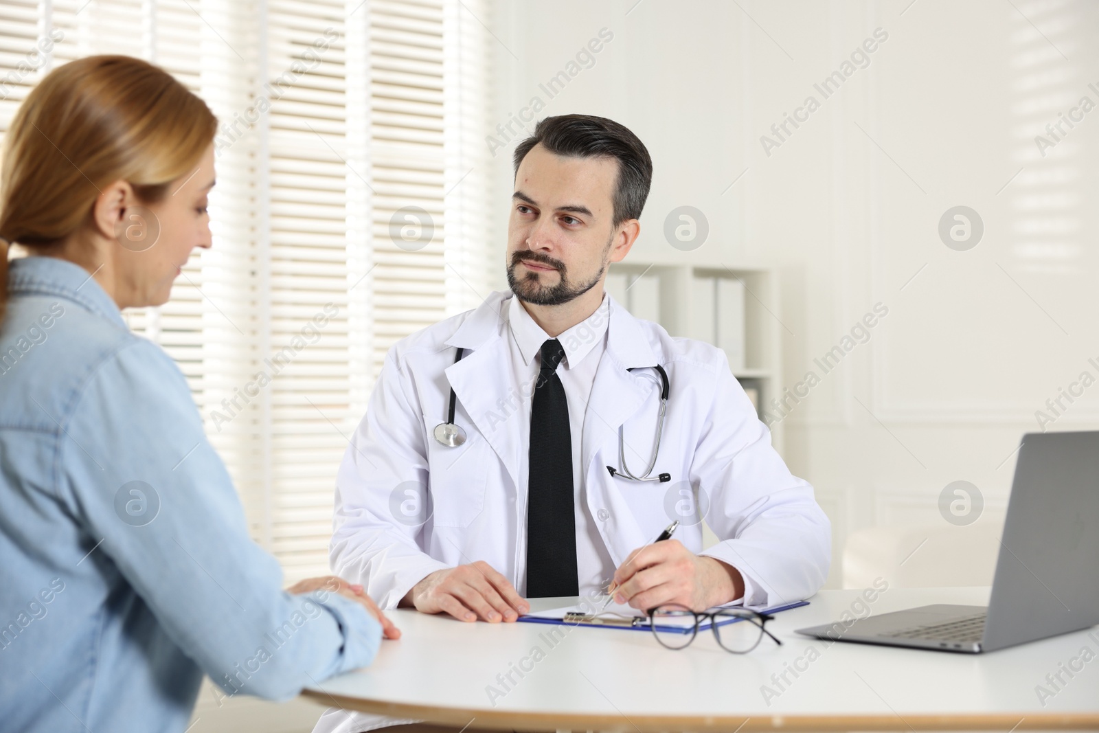 Photo of Cardiologist consulting patient at table in clinic