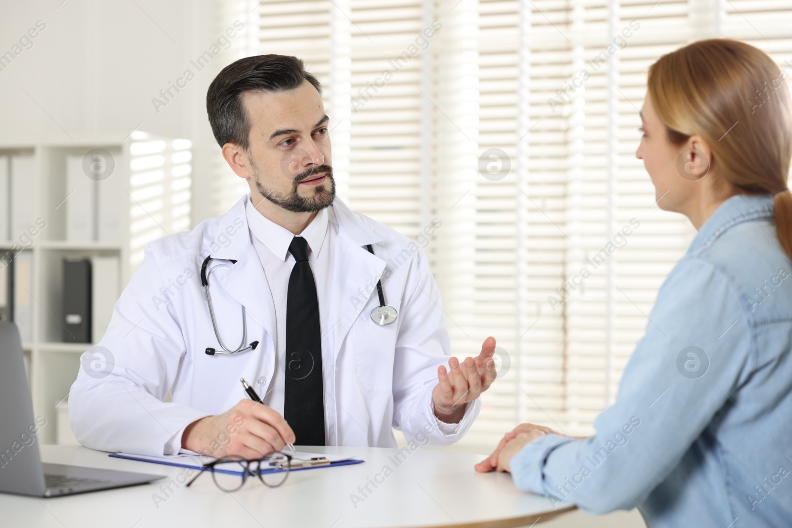 Photo of Cardiologist consulting patient at table in clinic