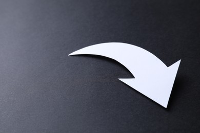 Photo of One white paper arrow on black background, closeup. Space for text