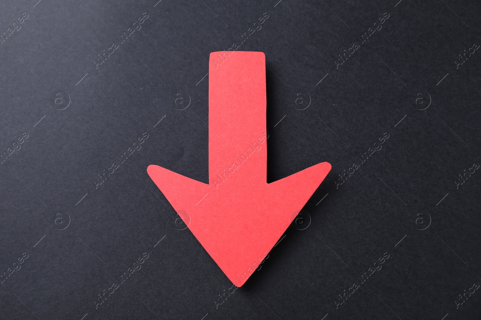 Photo of One red paper arrow on black background, top view