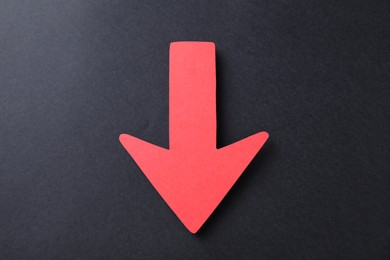 Photo of One red paper arrow on black background, top view