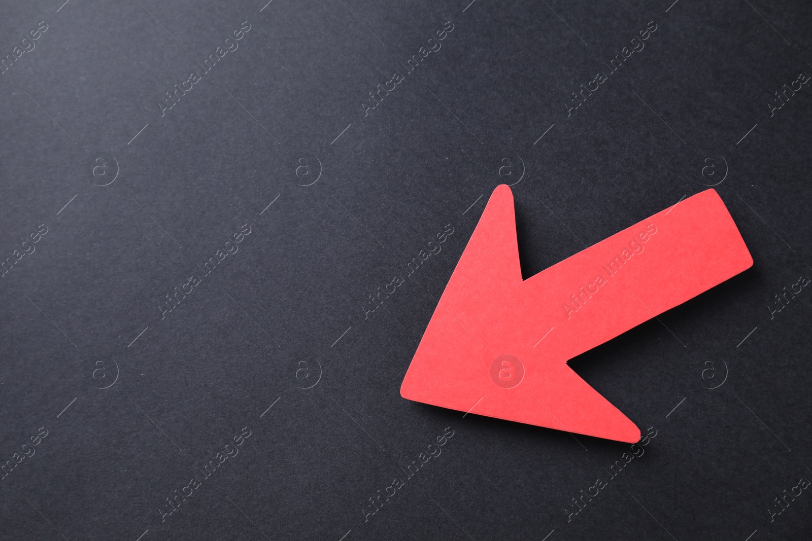 Photo of One red paper arrow on black background, top view. Space for text