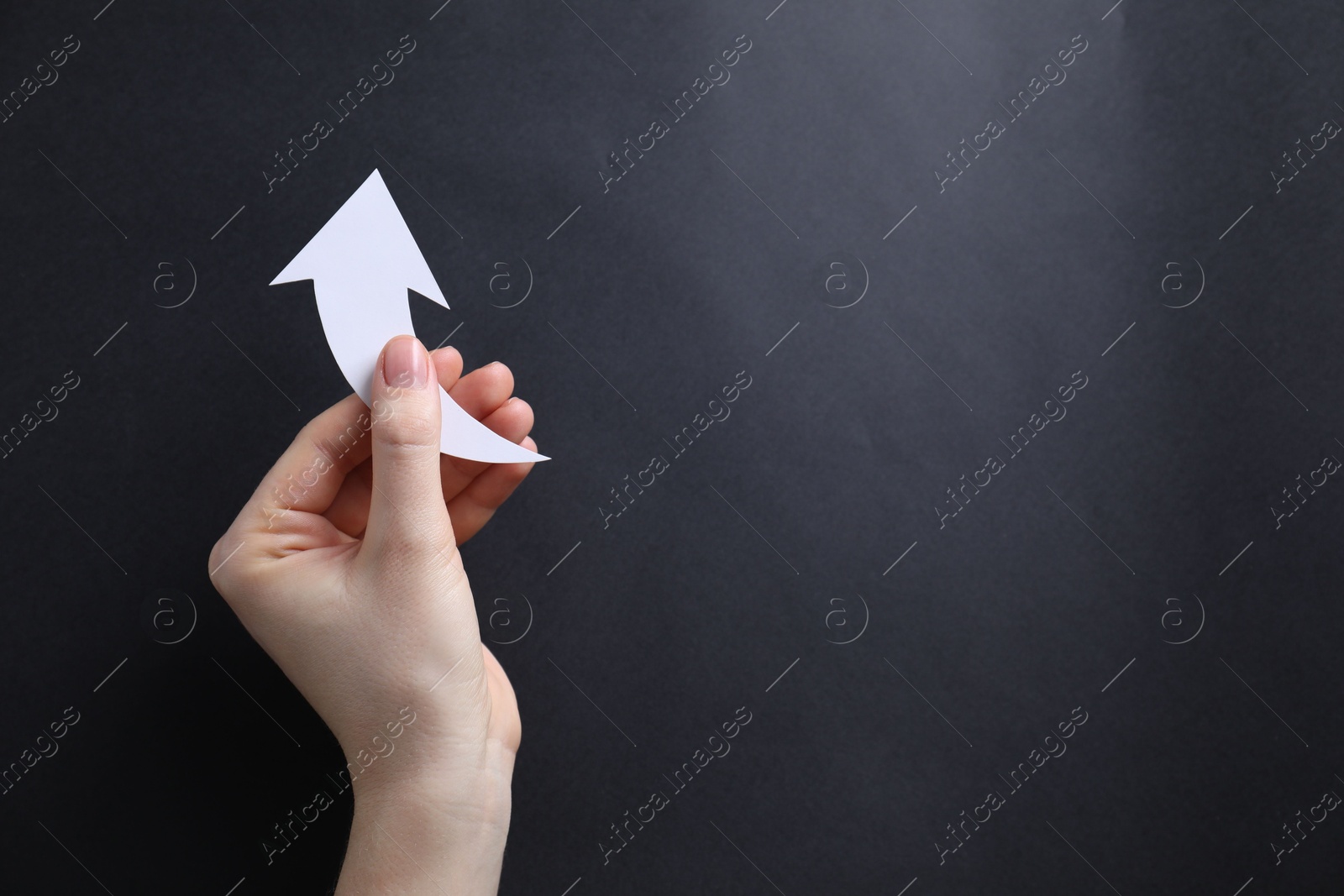 Photo of Woman with paper arrow on black background, top view. Space for text