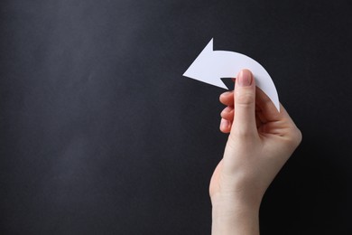 Photo of Woman with paper arrow on black background, top view. Space for text