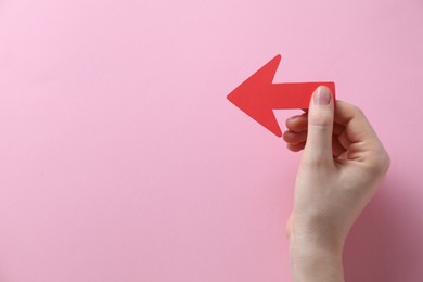 Photo of Woman with paper arrow on pink background, top view. Space for text