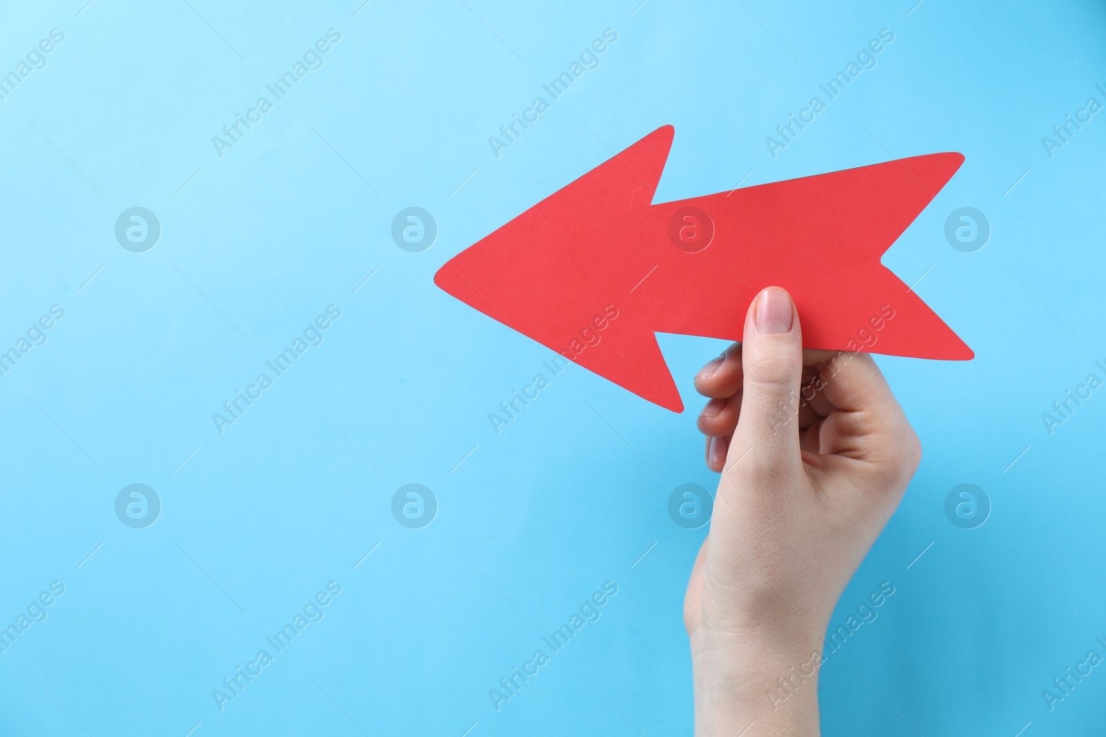 Photo of Woman with paper arrow on light blue background, top view. Space for text