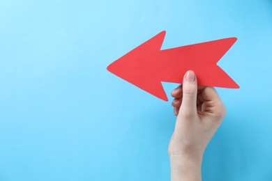 Photo of Woman with paper arrow on light blue background, top view. Space for text