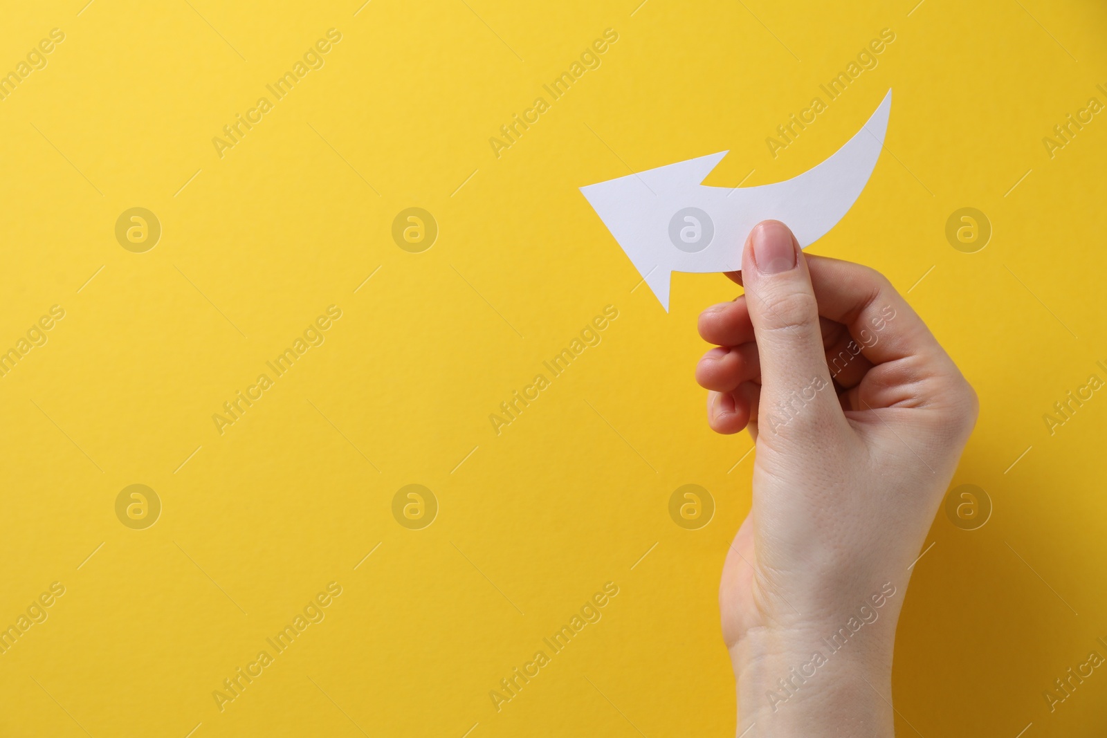 Photo of Woman with paper arrow on yellow background, top view. Space for text