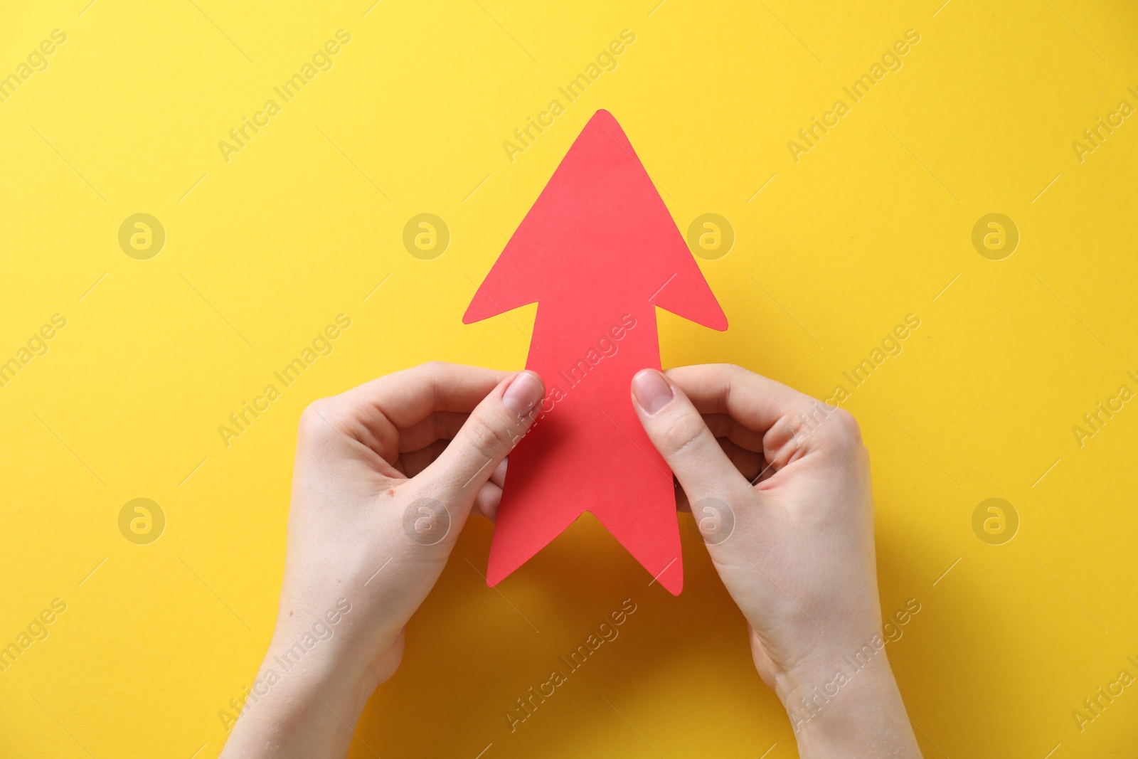 Photo of Woman with paper arrow on yellow background, top view