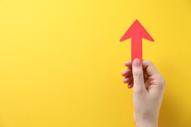 Photo of Woman with paper arrow on yellow background, top view. Space for text