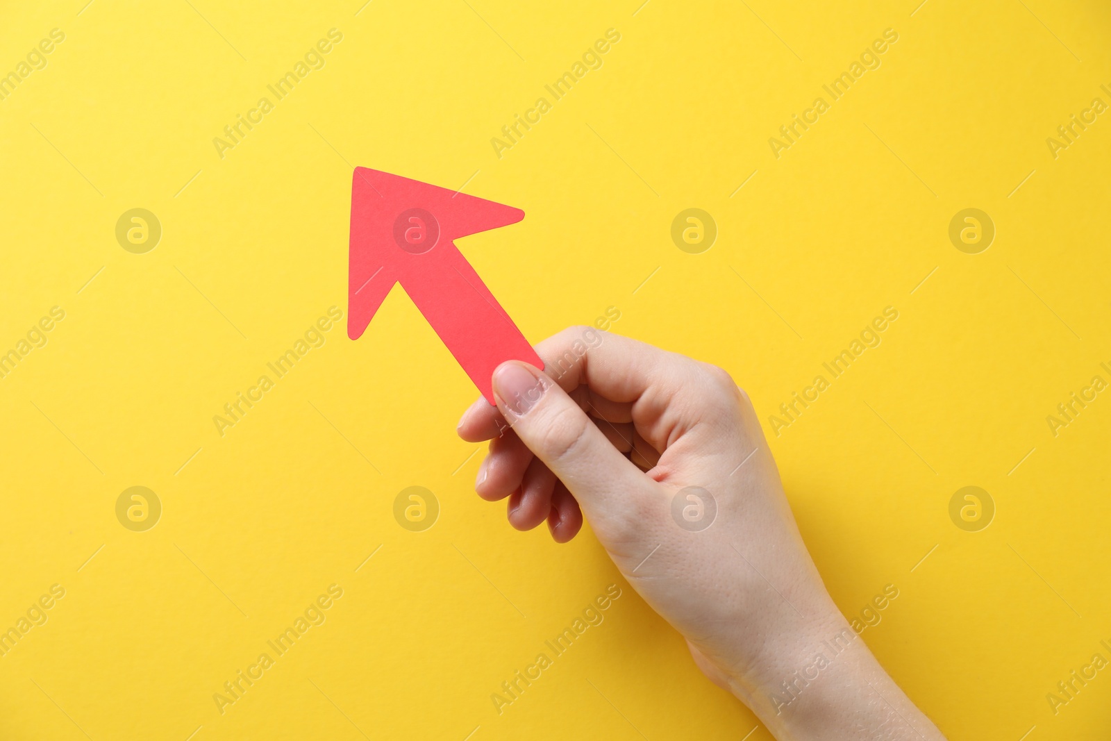 Photo of Woman with paper arrow on yellow background, top view