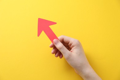 Photo of Woman with paper arrow on yellow background, top view