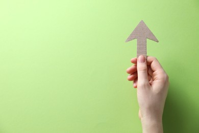 Photo of Woman with paper arrow on light green background, top view. Space for text