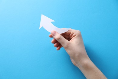 Photo of Woman with paper arrow on light blue background, top view. Space for text