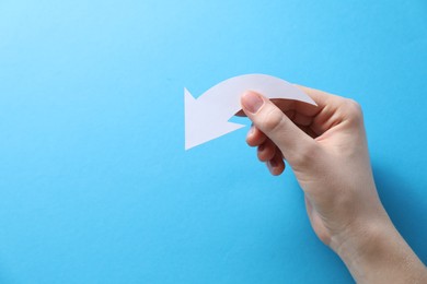 Photo of Woman with paper arrow on light blue background, top view. Space for text