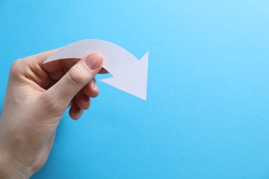 Photo of Woman with paper arrow on light blue background, top view. Space for text