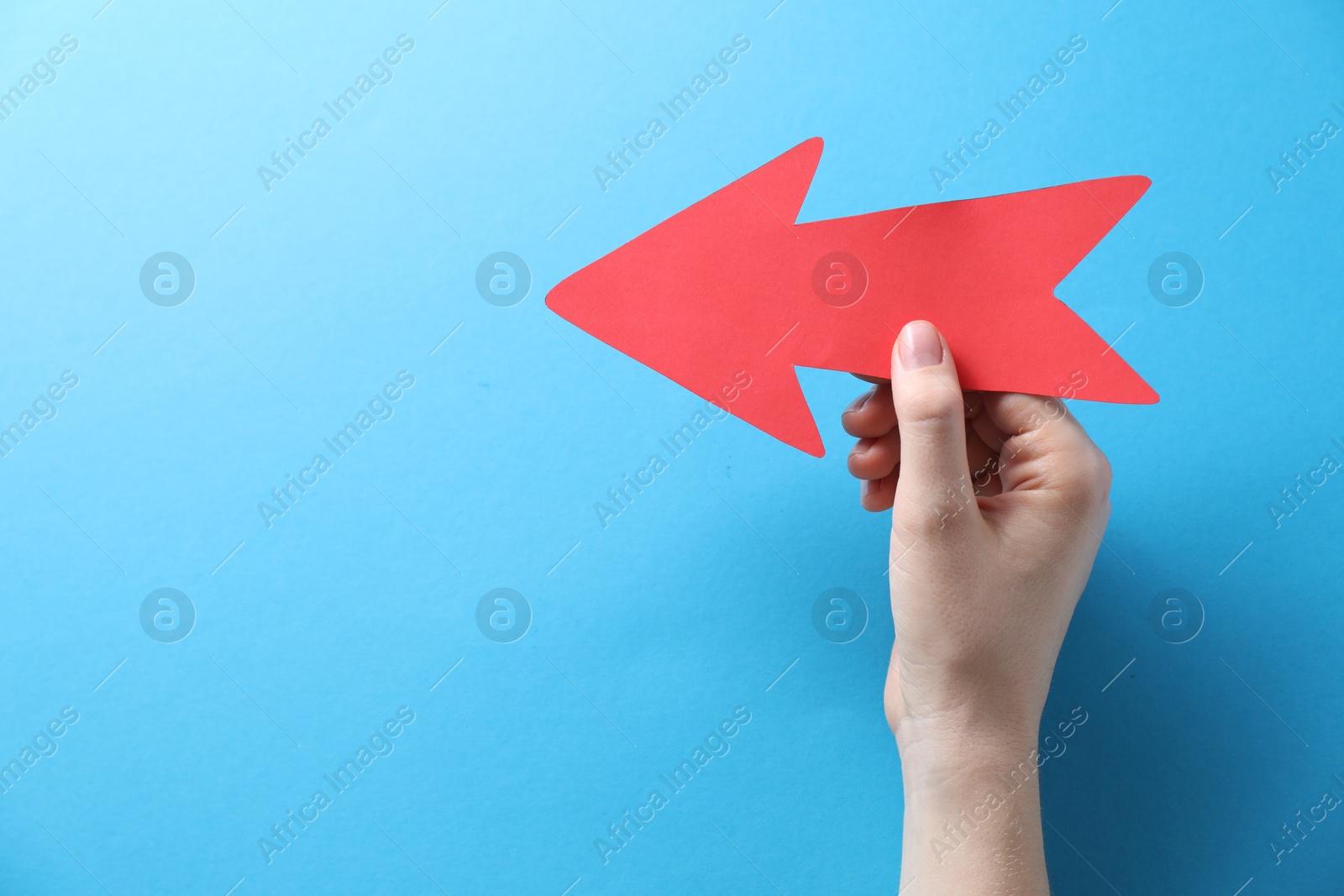 Photo of Woman with paper arrow on light blue background, top view. Space for text