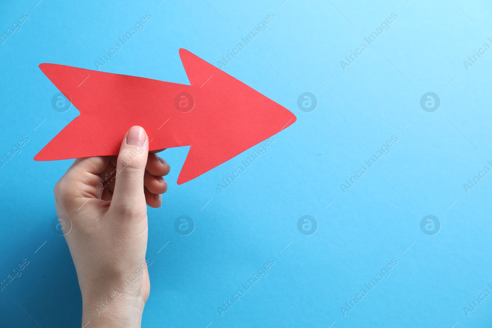 Photo of Woman with paper arrow on light blue background, top view. Space for text