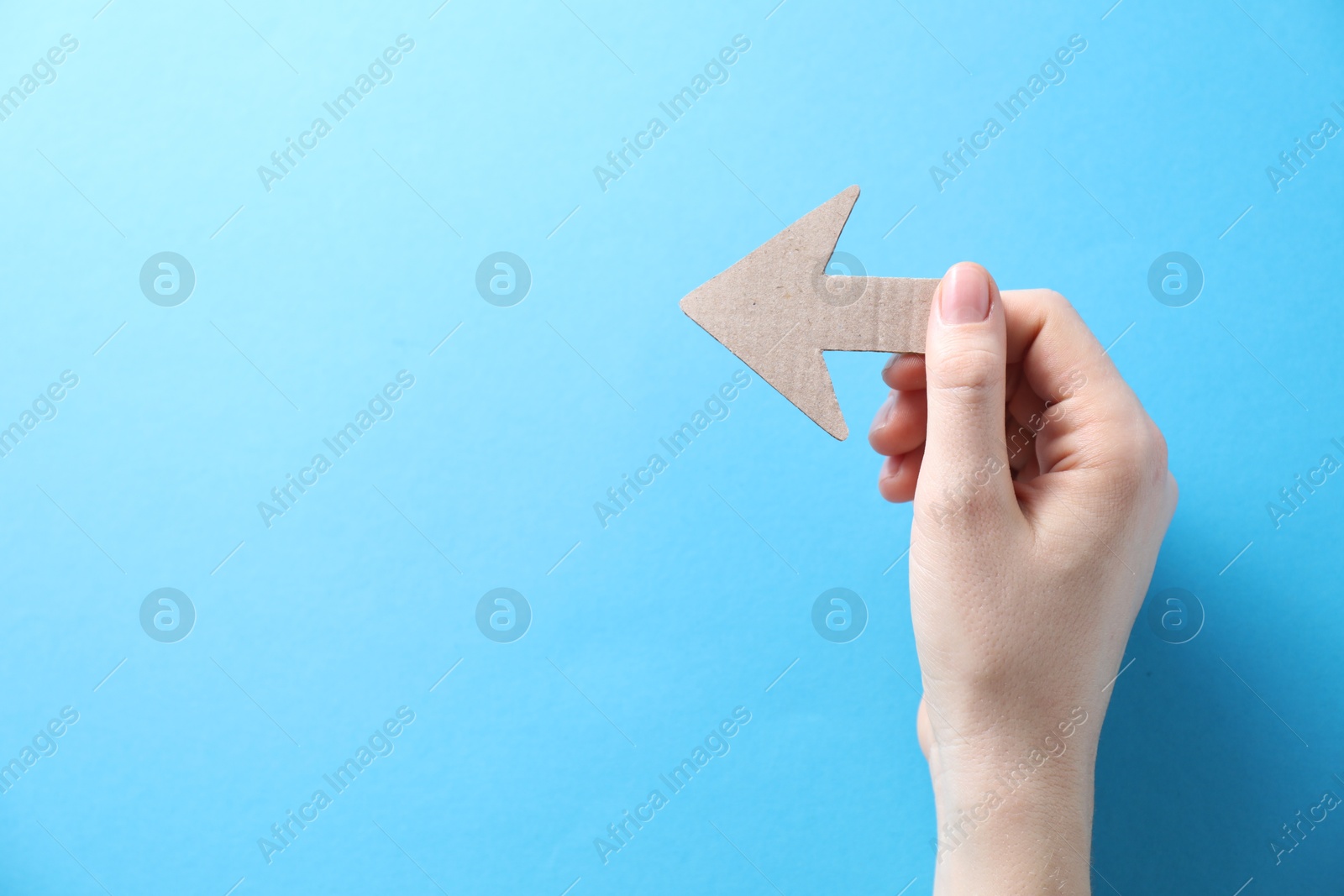 Photo of Woman with paper arrow on light blue background, top view. Space for text