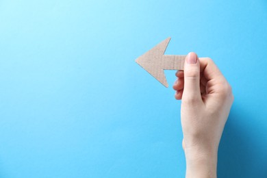 Photo of Woman with paper arrow on light blue background, top view. Space for text