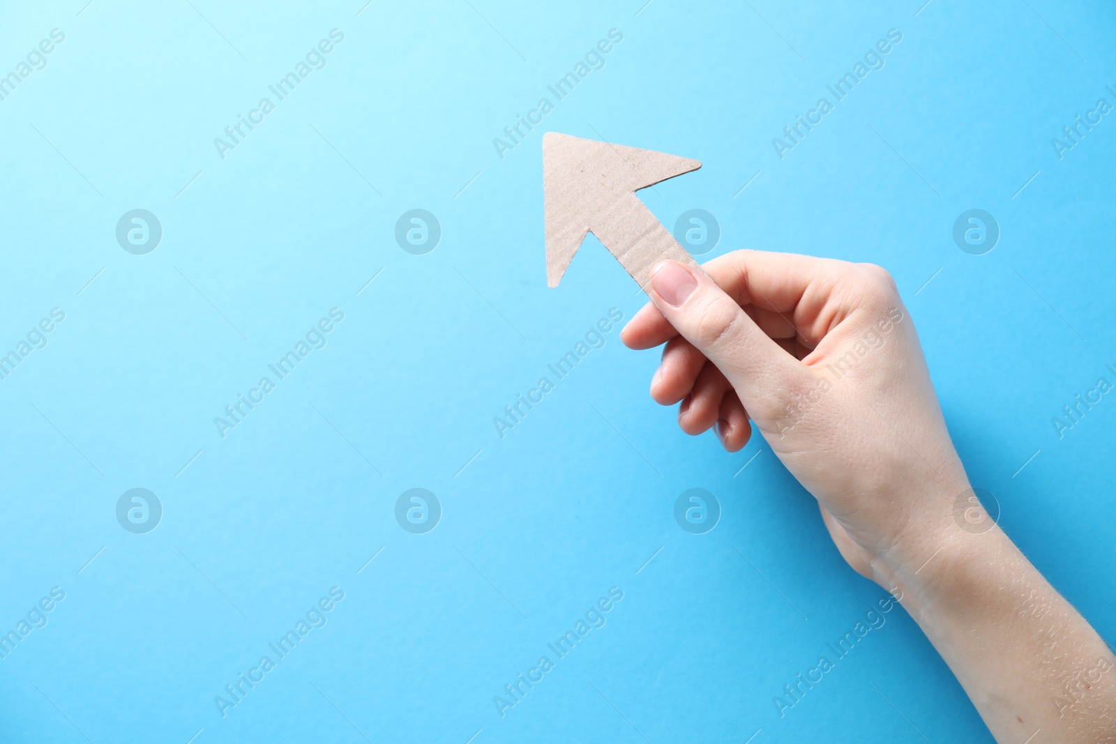 Photo of Woman with paper arrow on light blue background, top view. Space for text