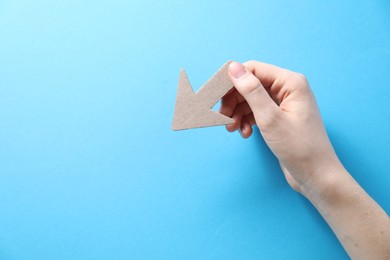 Photo of Woman with paper arrow on light blue background, top view. Space for text