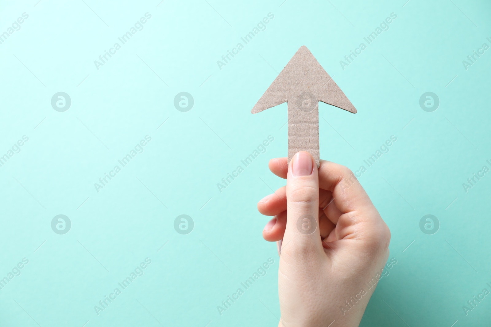 Photo of Woman with paper arrow on turquoise background, top view. Space for text