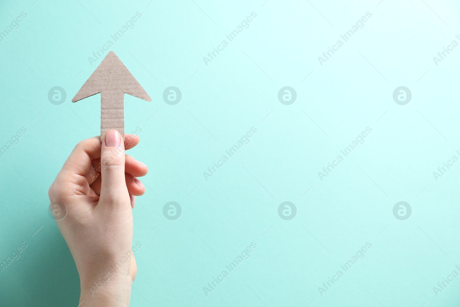 Photo of Woman with paper arrow on turquoise background, top view. Space for text