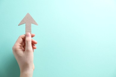 Photo of Woman with paper arrow on turquoise background, top view. Space for text