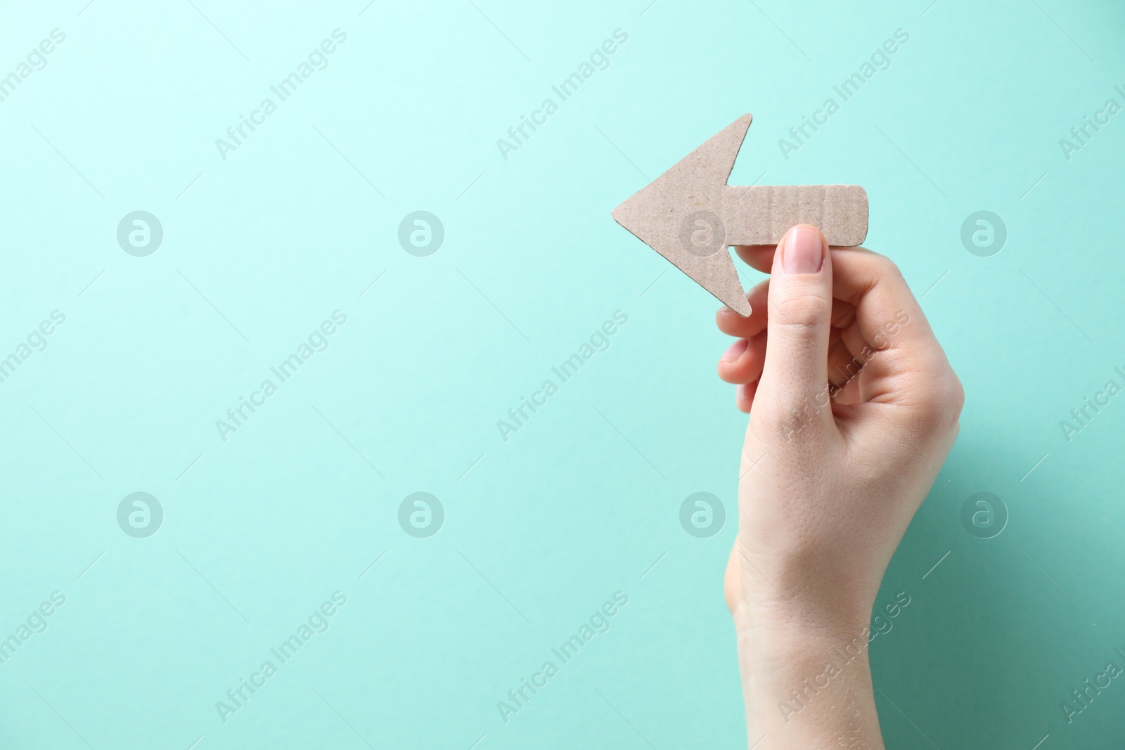 Photo of Woman with paper arrow on turquoise background, top view. Space for text