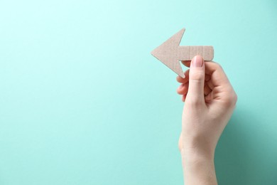 Photo of Woman with paper arrow on turquoise background, top view. Space for text