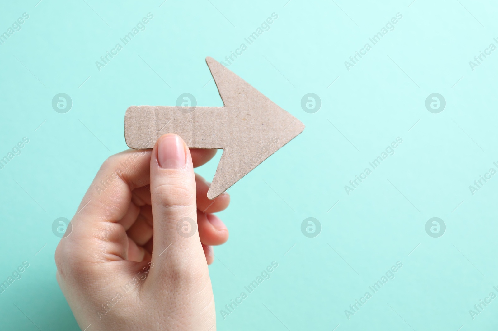 Photo of Woman with paper arrow on turquoise background, top view. Space for text