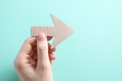 Photo of Woman with paper arrow on turquoise background, top view. Space for text