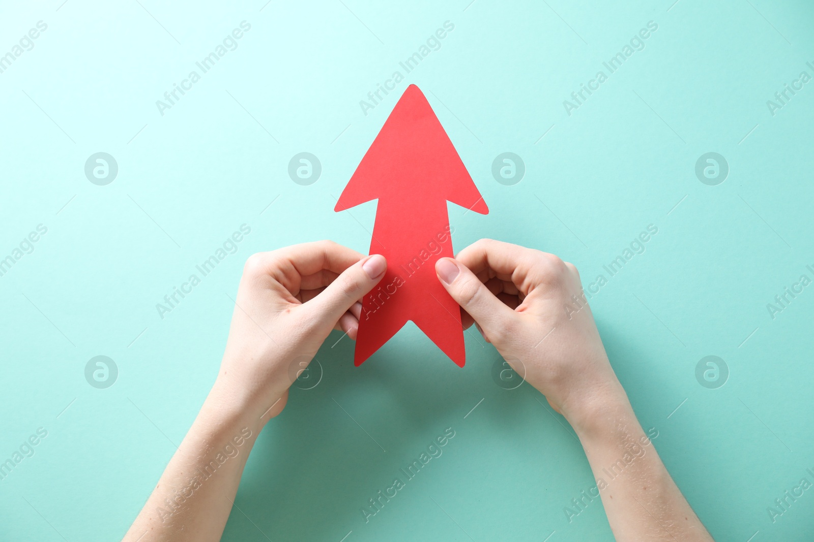 Photo of Woman with paper arrow on turquoise background, top view