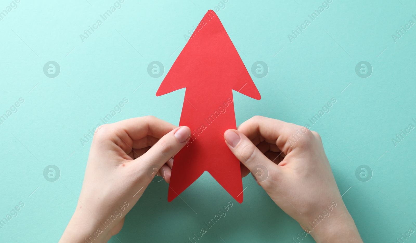 Photo of Woman with paper arrow on turquoise background, top view