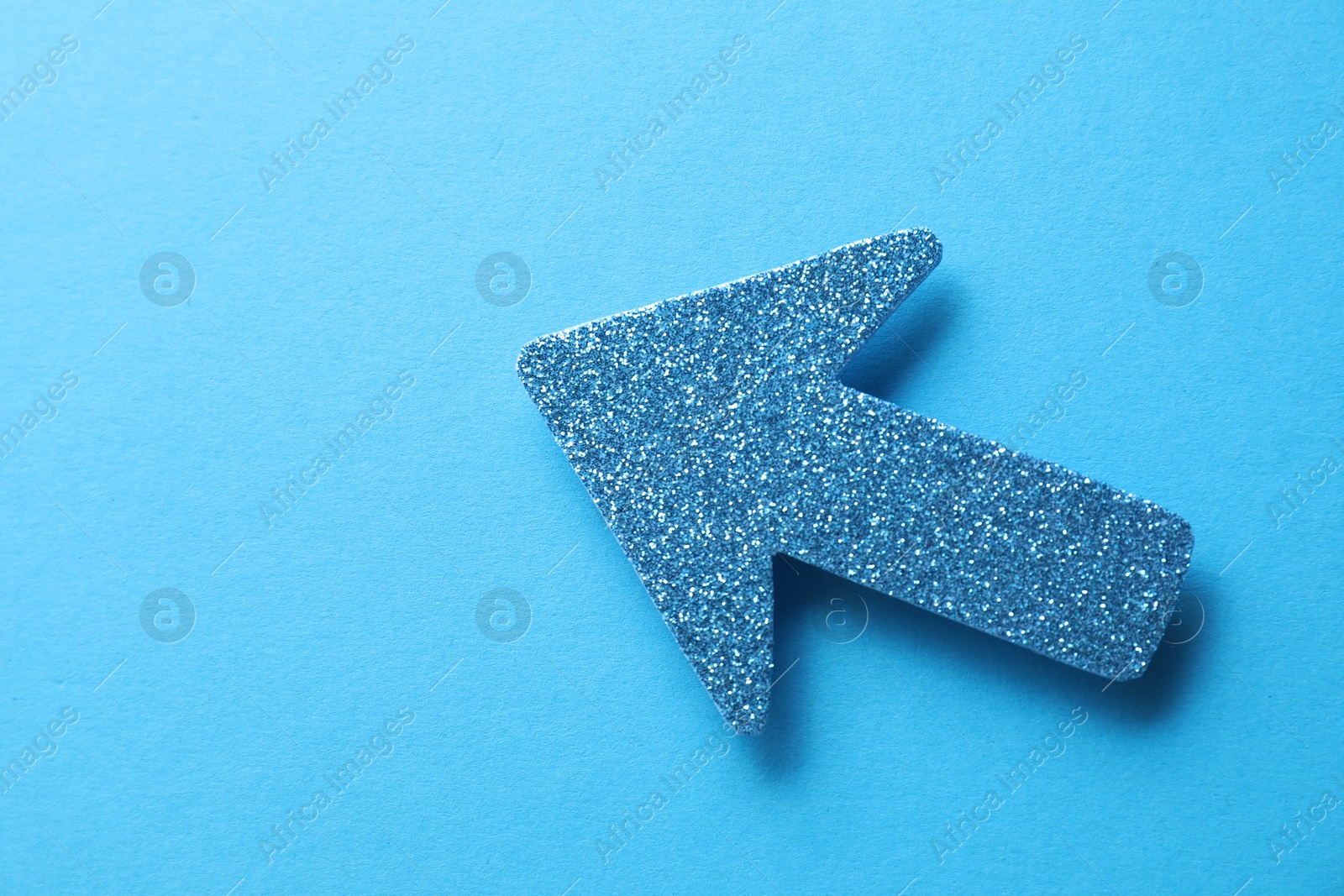 Photo of One glitter arrow on light blue background, top view. Space for text