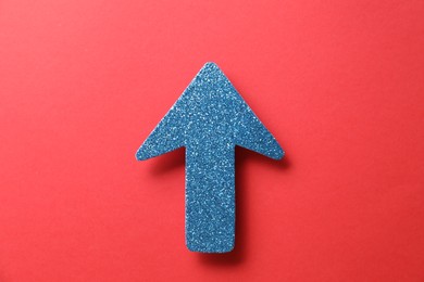 Photo of One glitter arrow on red background, top view