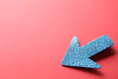 Photo of One glitter arrow on red background, closeup. Space for text