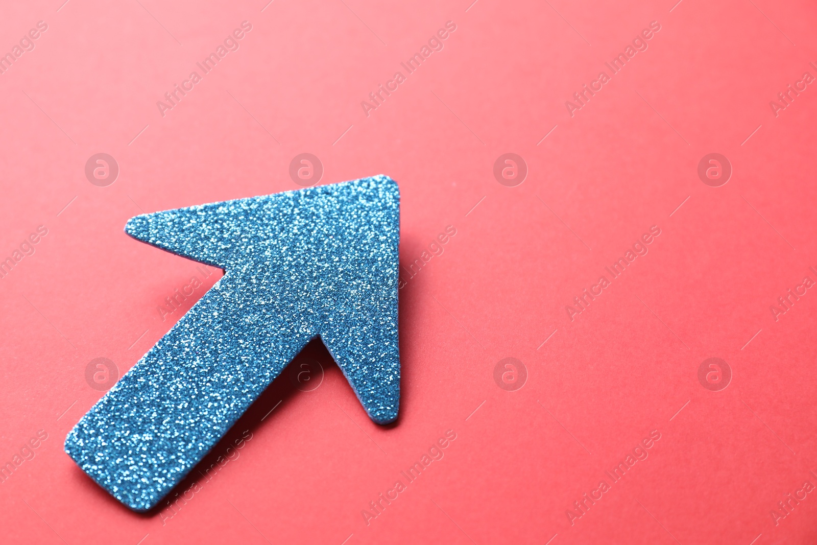 Photo of One glitter arrow on red background, closeup. Space for text