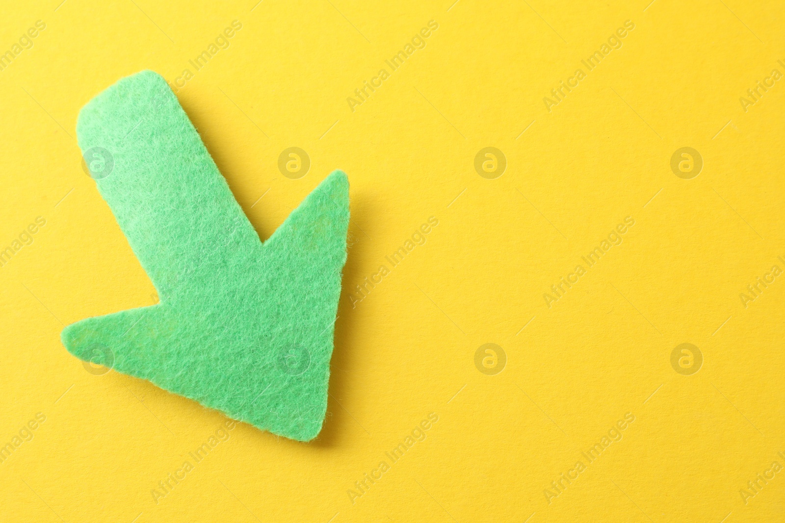 Photo of One green arrow on yellow background, top view. Space for text