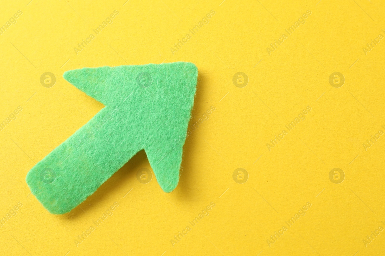 Photo of One green arrow on yellow background, top view. Space for text