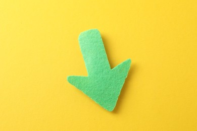 Photo of One green arrow on yellow background, top view