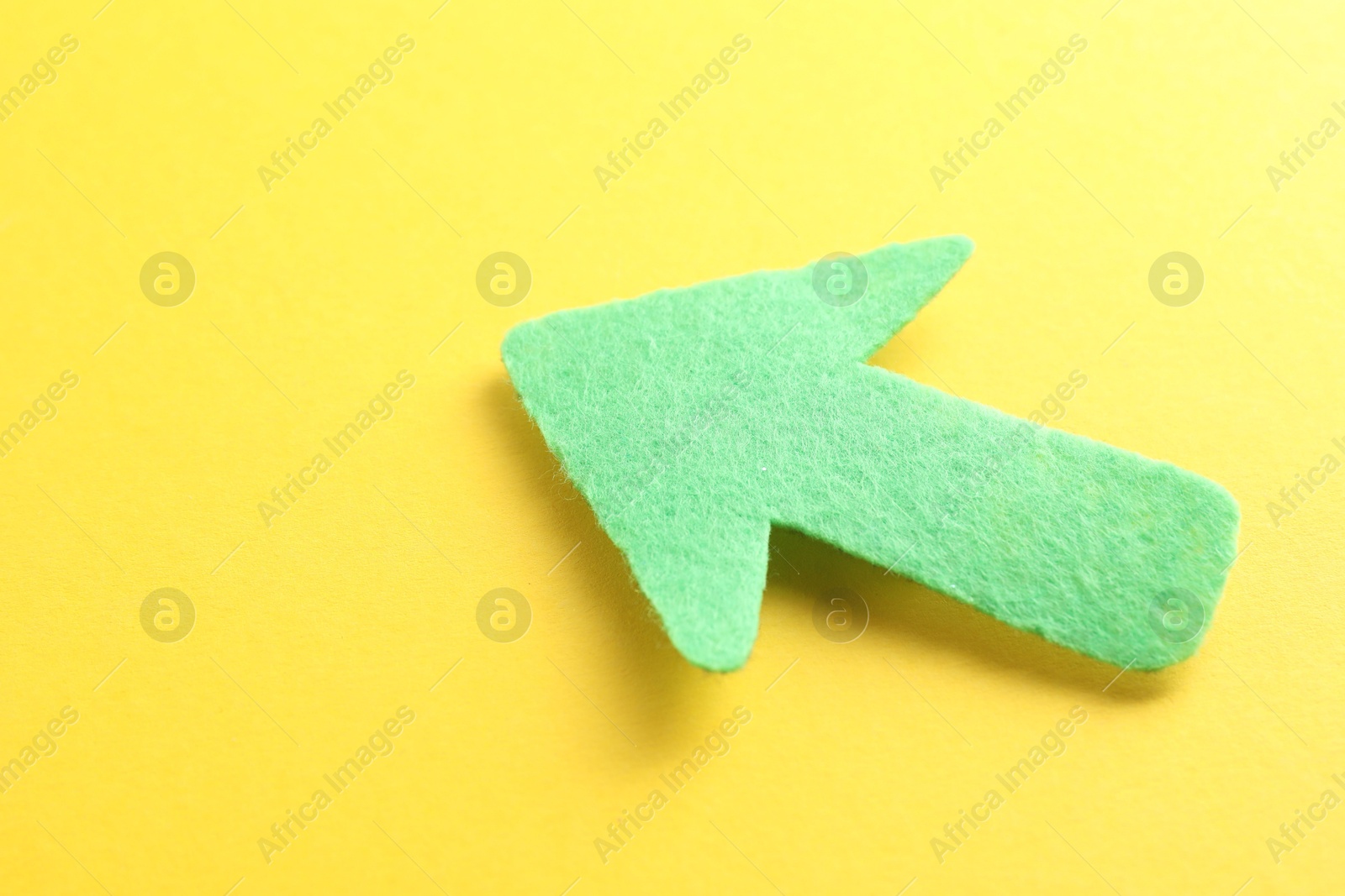 Photo of One green arrow on yellow background, closeup