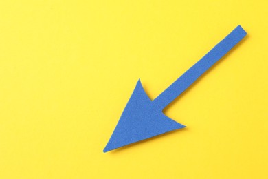 Photo of One blue arrow on yellow background, top view. Space for text