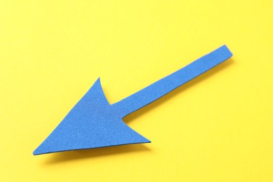 Photo of One blue arrow on yellow background, closeup