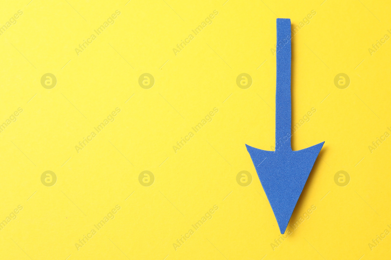 Photo of One blue arrow on yellow background, top view. Space for text