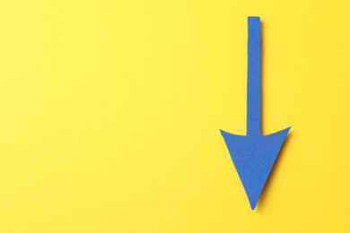 Photo of One blue arrow on yellow background, top view. Space for text