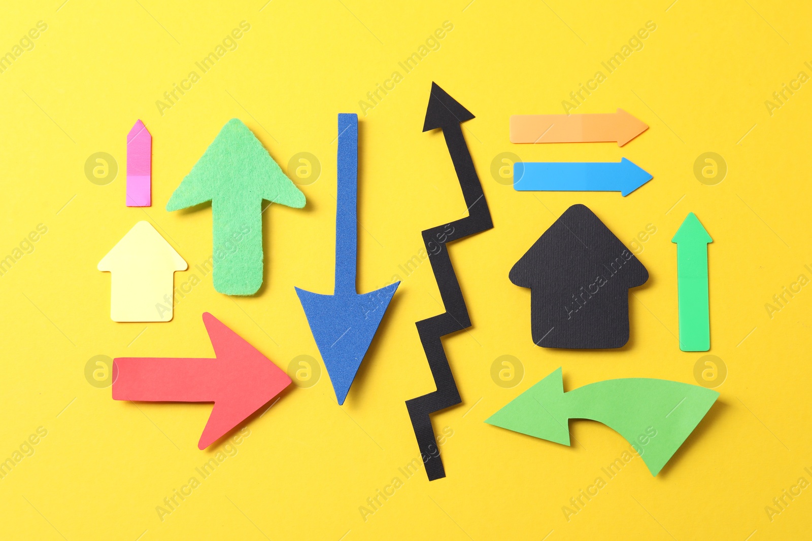 Photo of Different paper arrows on yellow background, flat lay