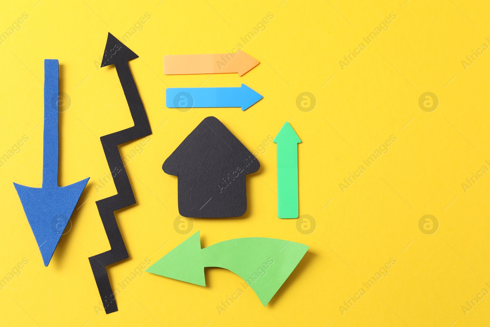 Photo of Different paper arrows on yellow background, flat lay