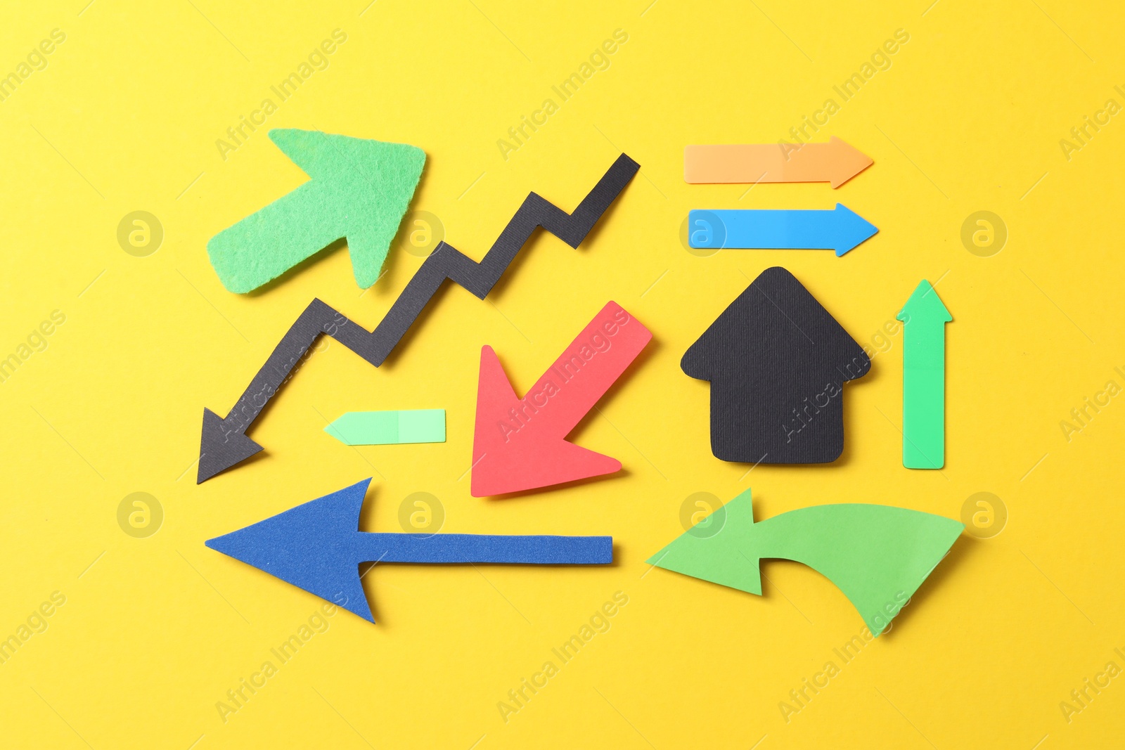 Photo of Different paper arrows on yellow background, flat lay